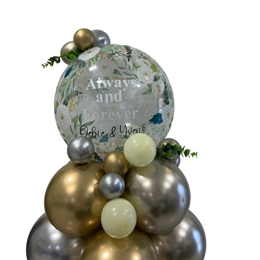 Decorative balloon arrangement with floral balloon and text against a plain background