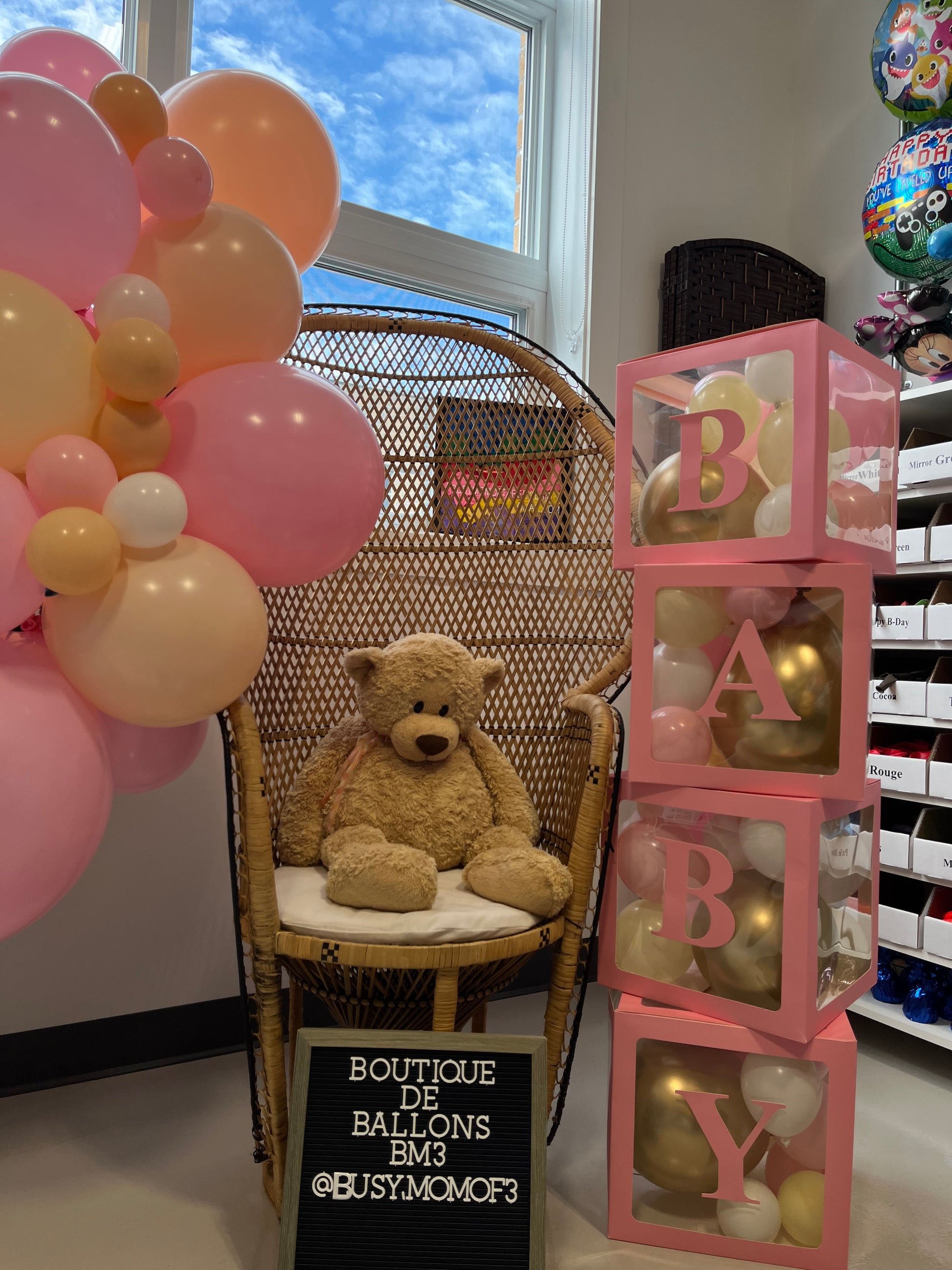 Pink baby balloon boxes with letters and a teddy bear